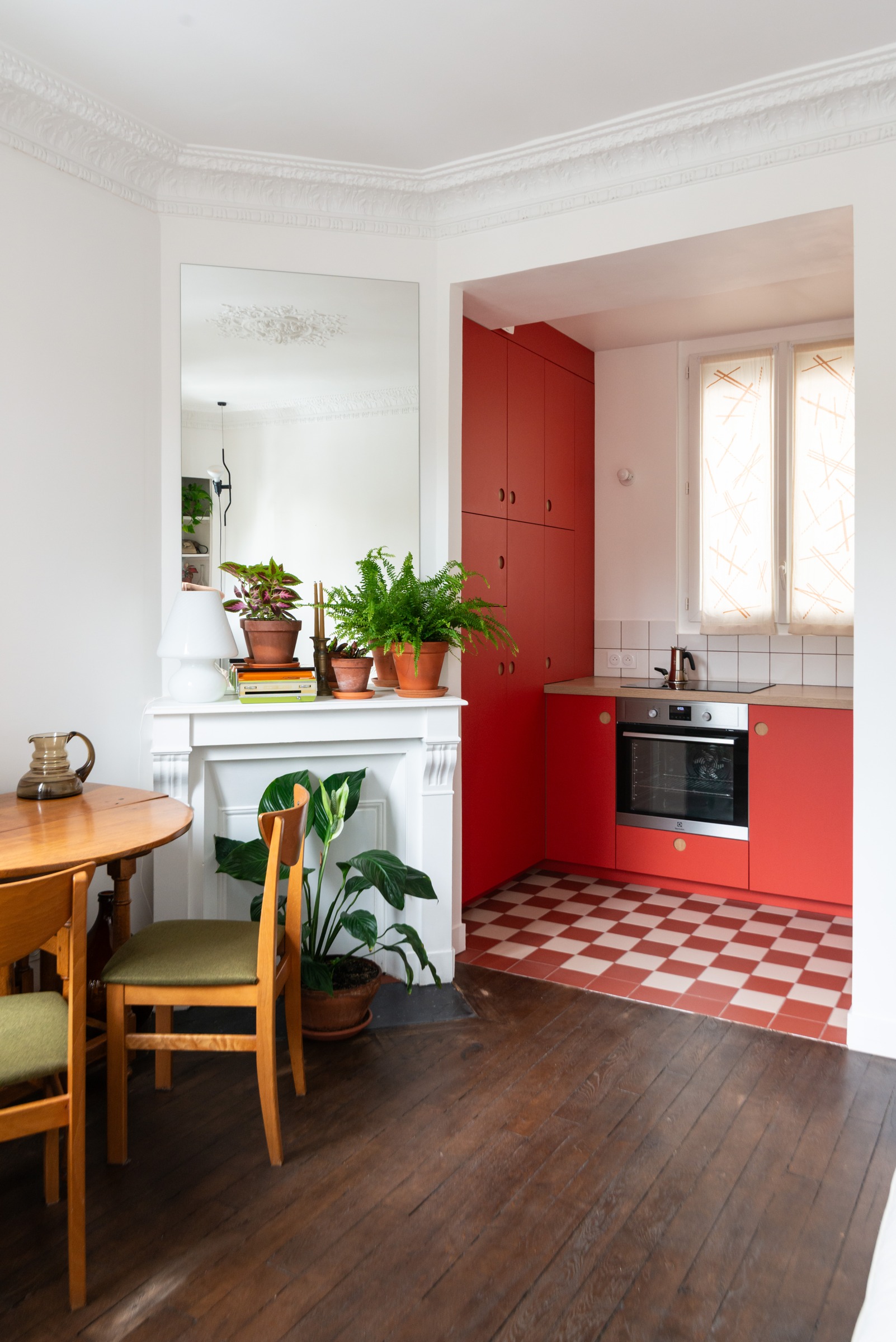 Vue de la pièce de vie vers la cuisine rouge et son sol en damier à Paris 20e