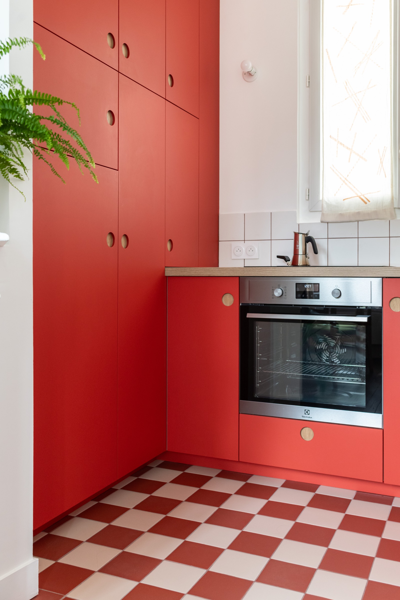 Cuisine rouge avec four encastré, façades sur mesure et sol en damier