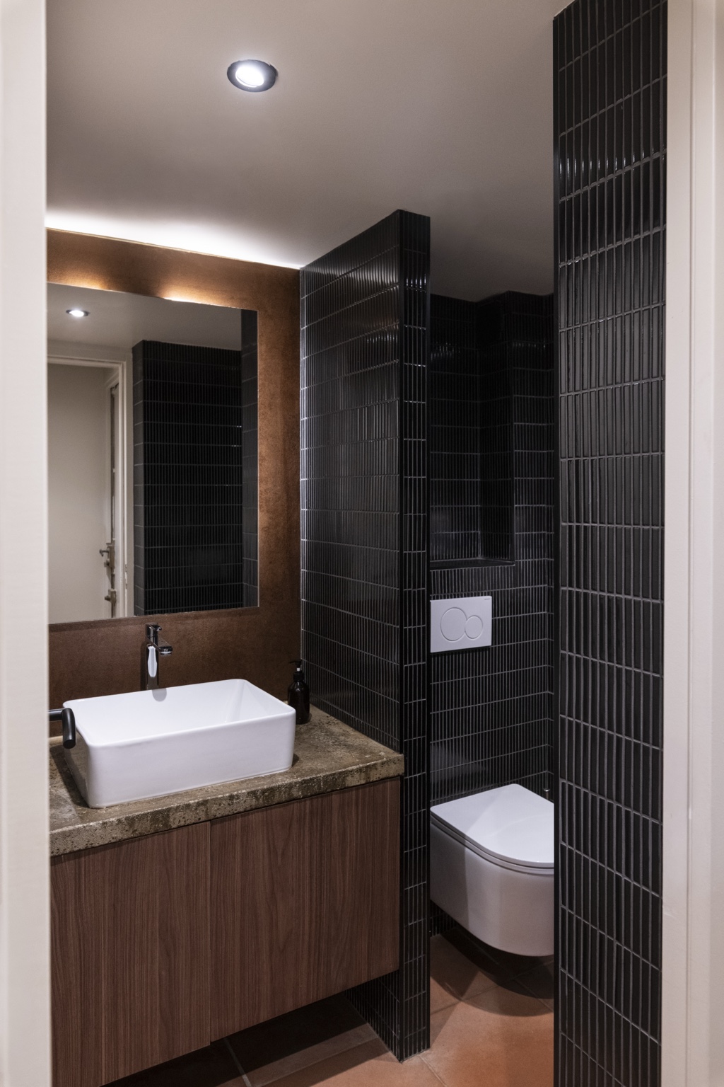 Sanitaires du café du Marais avec vasque, meuble en bois et carrelage sombre