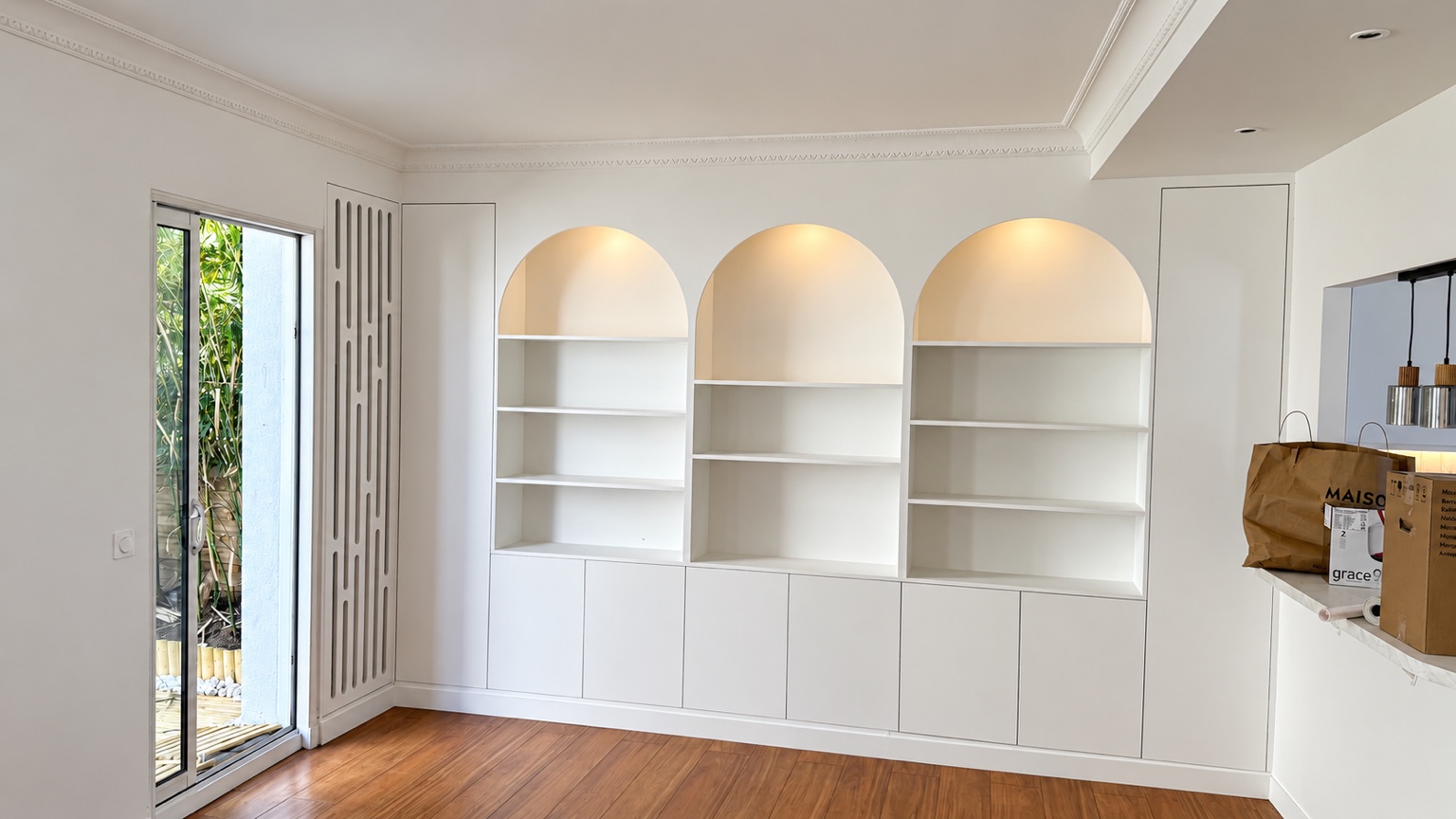 Bibliothèque blanche sur mesure avec trois niches en arches éclairées dans une maison à Colombes