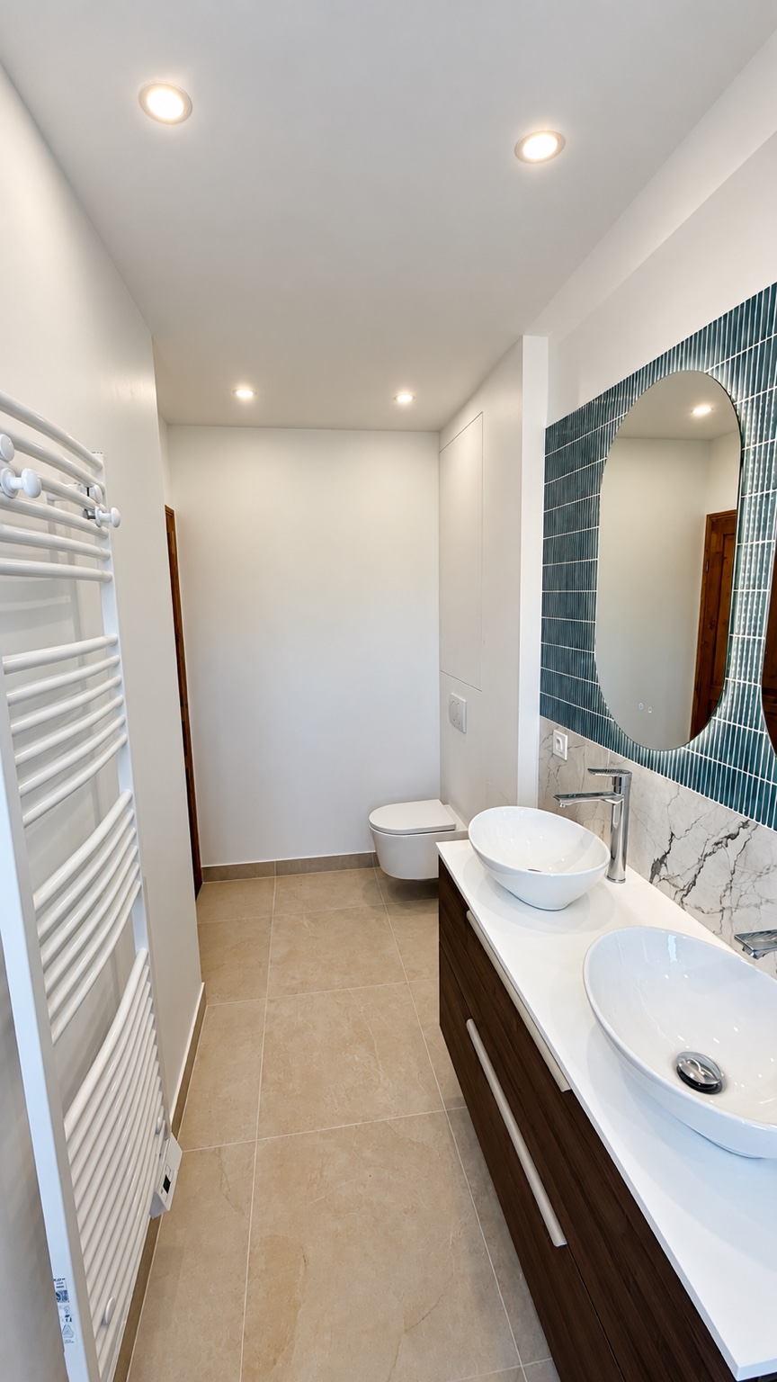 Salle de bains à Colombes avec double vasque, meuble en bois et deux miroirs arrondis