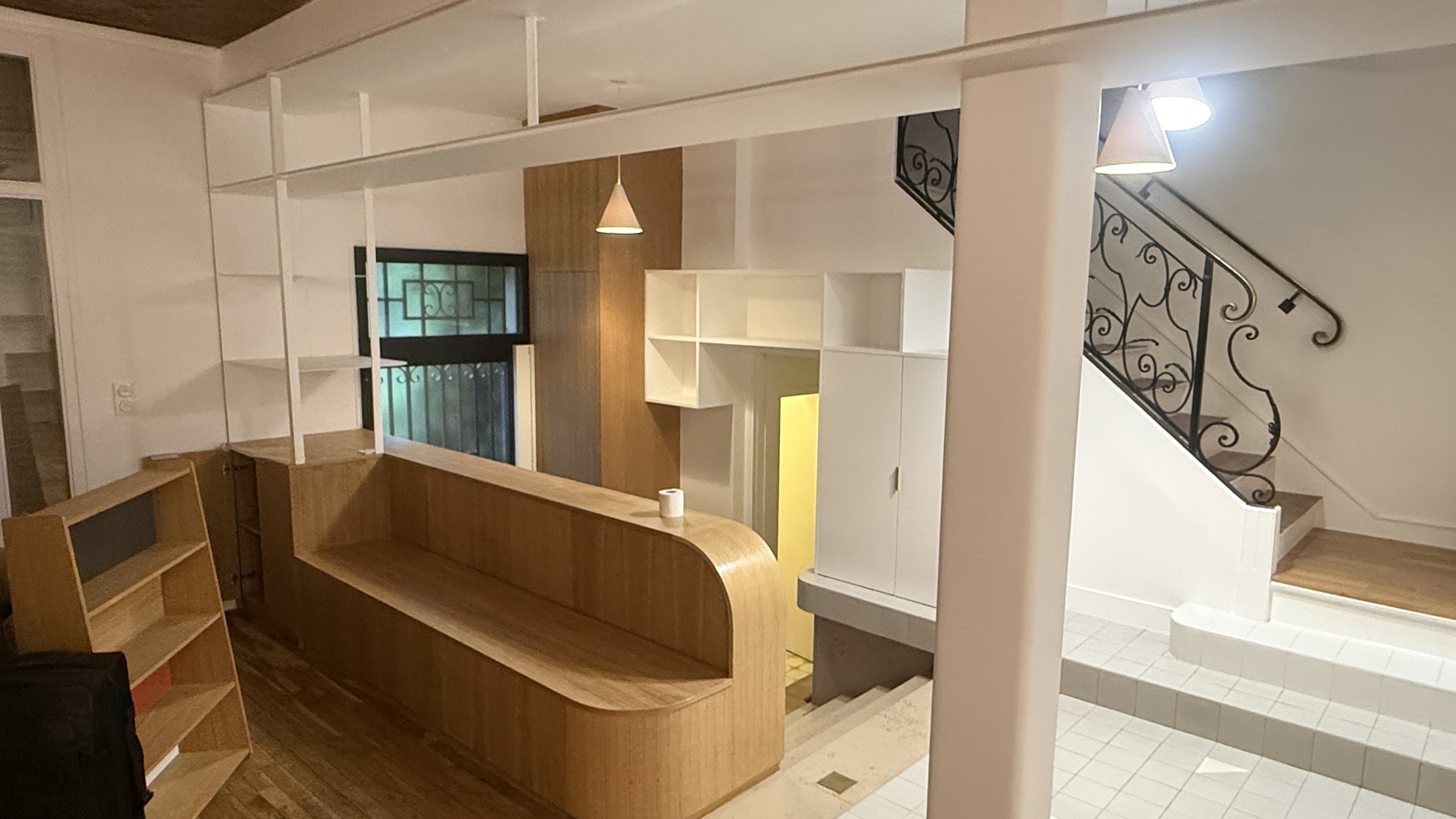 Vue d’ensemble de la cuisine en bois, avec îlot central et escalier ancien à Paris 13e