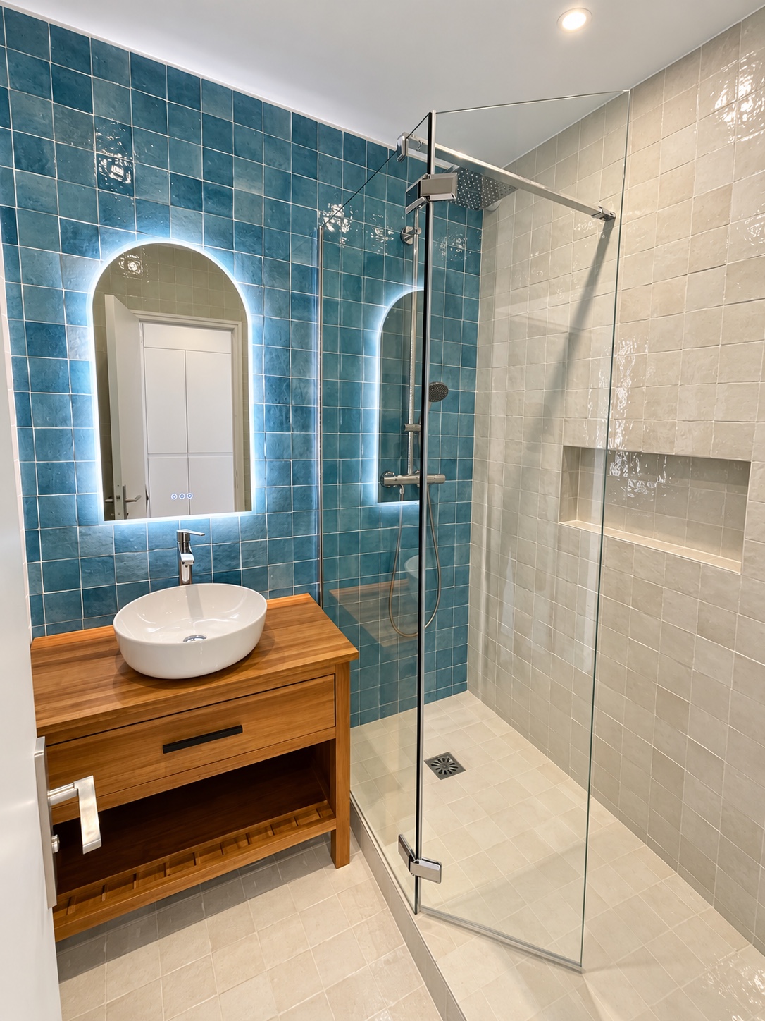 Salle de bains avec carrelage bleu, meuble vasque en bois et douche vitrée