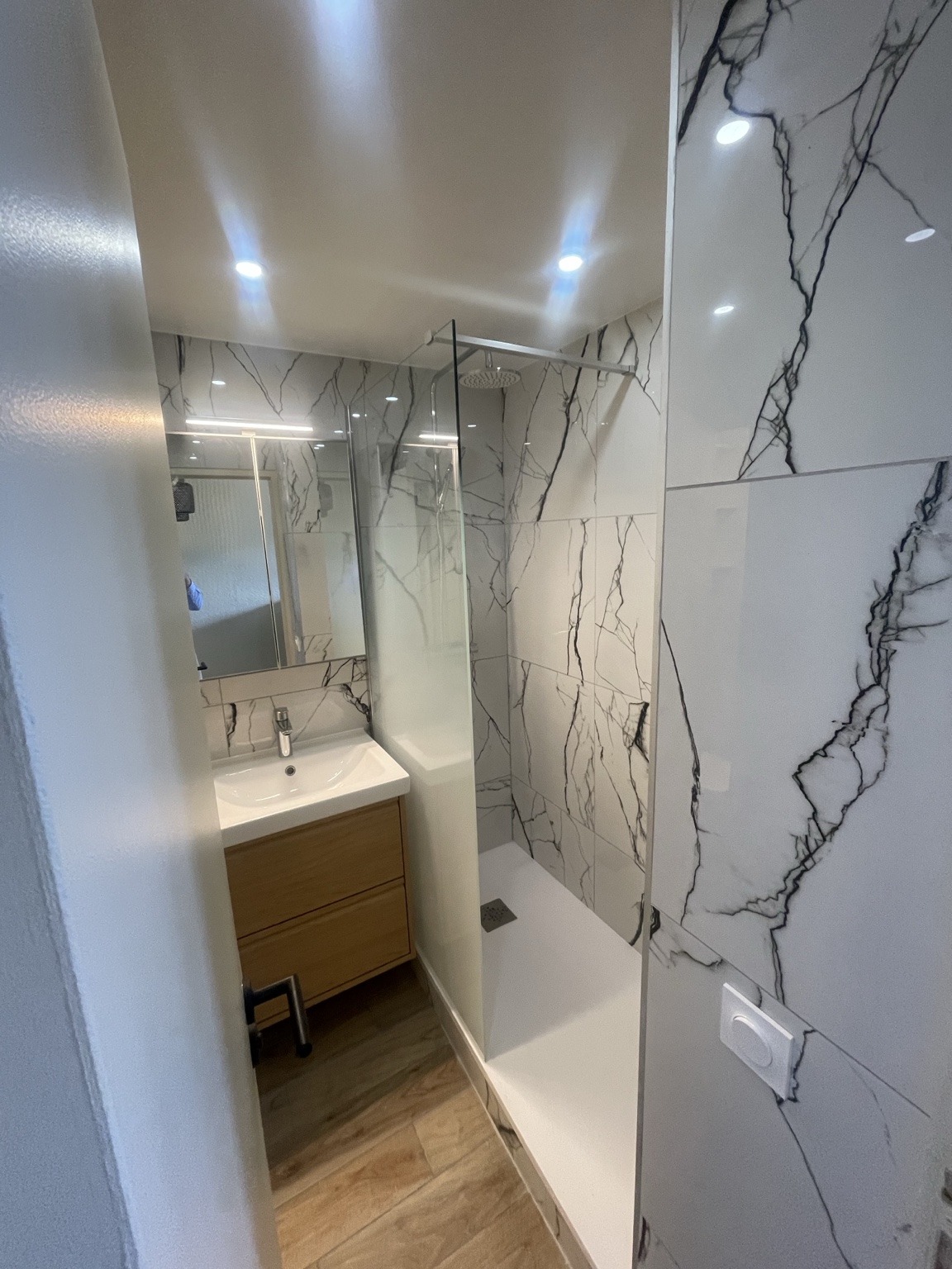 Salle d’eau en longueur avec douche et carrelage clair à veinage sombre