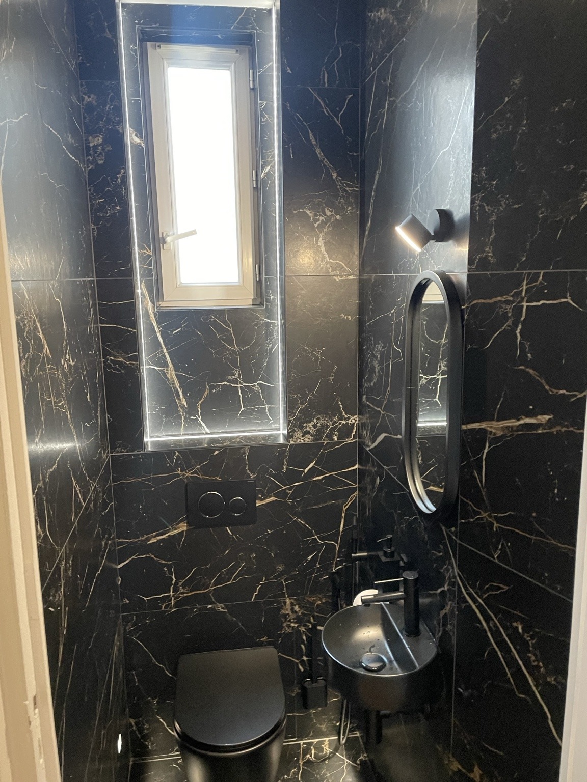 Douche avec carrelage sombre veiné et colonne de douche noire